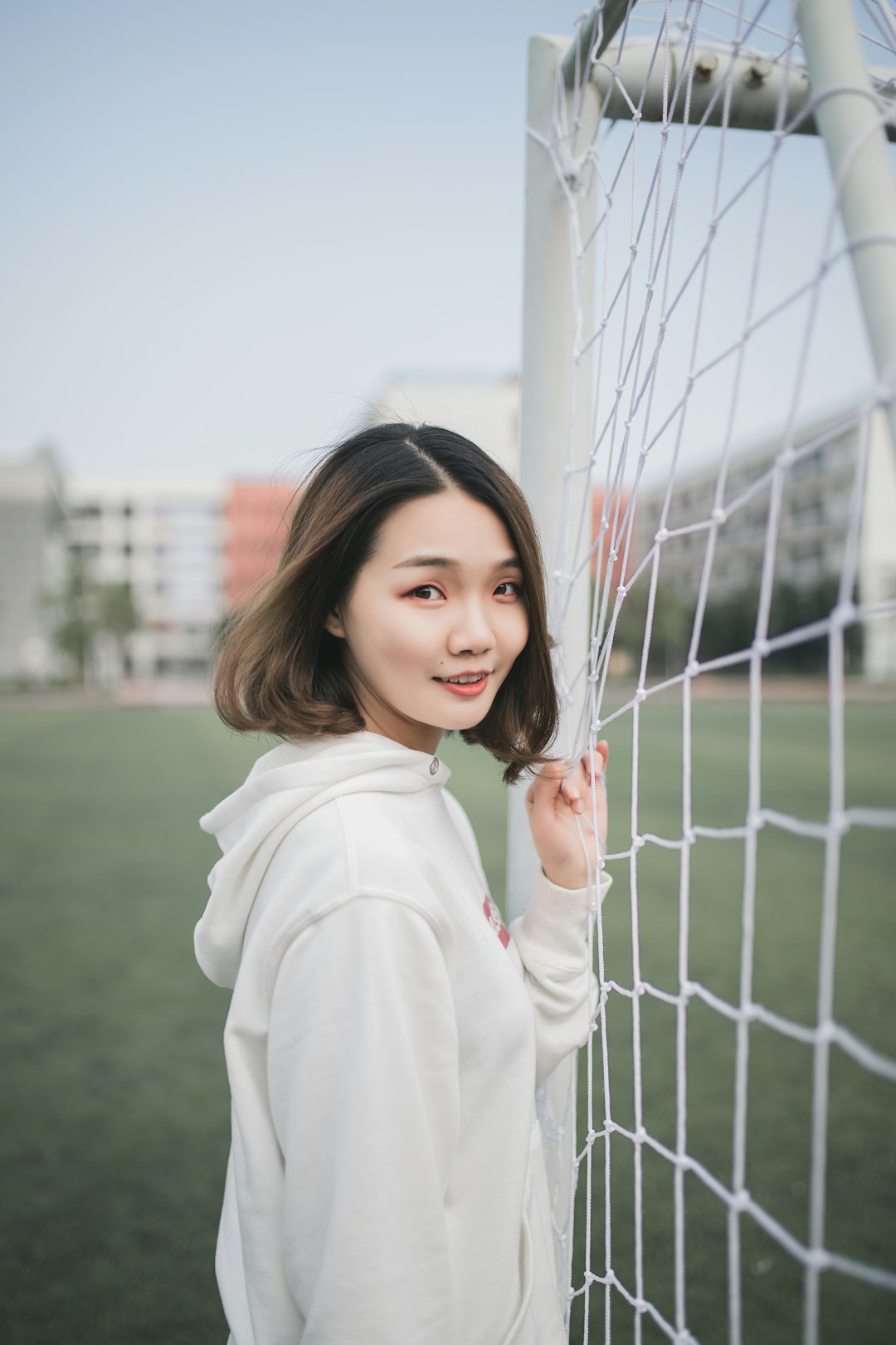 man in white pullover hoodie standing beside white goal net custom jersey soccer fan
