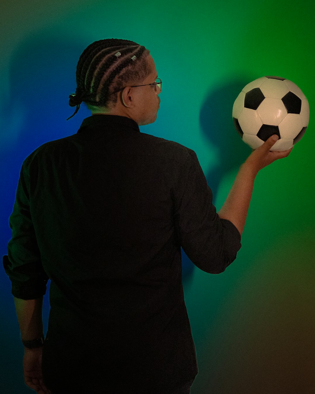 Person holding a soccer ball against colorful background soccer board game, football trivia, fan game night