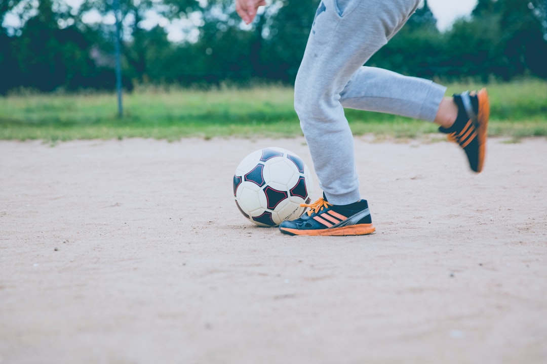 person plays soccer ball on white sands dribbling, soccer cones, backyard practice