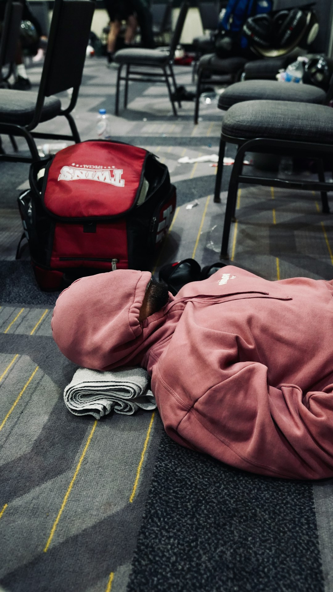 Person sleeping on the floor near a backpack. nba travel schedule fatigue court