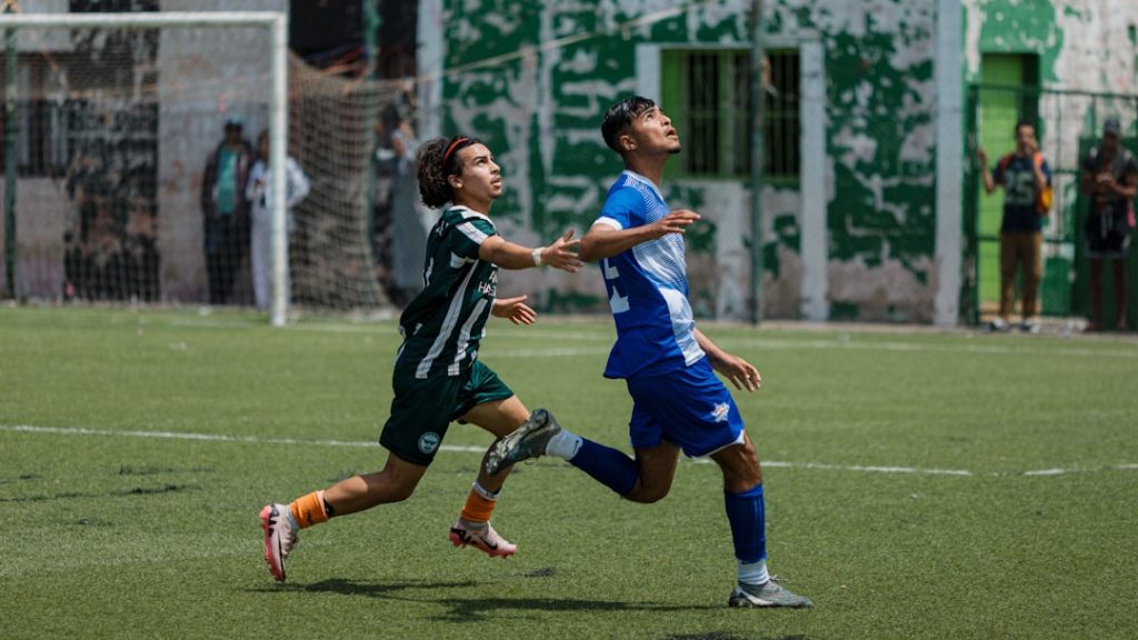 Two soccer players are running on the field. ronaldo messi football rivalry