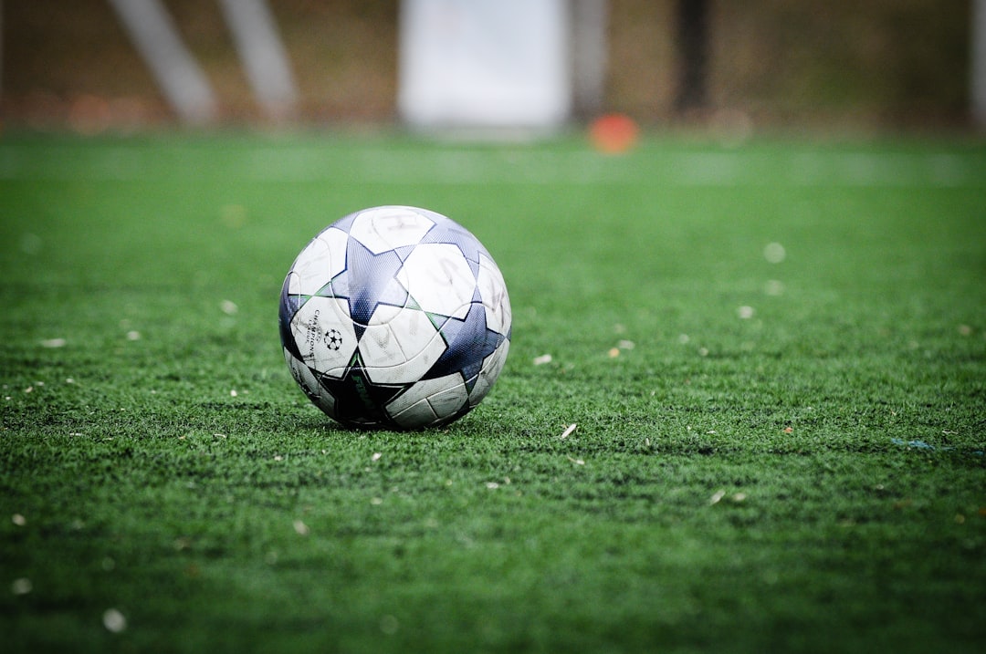 white and blue soccer ball on green grass field during daytime dribbling, soccer cones, backyard practice