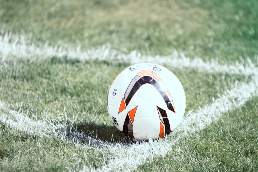 white, orange, and black soccer ball on field football gear training cones gloves ball