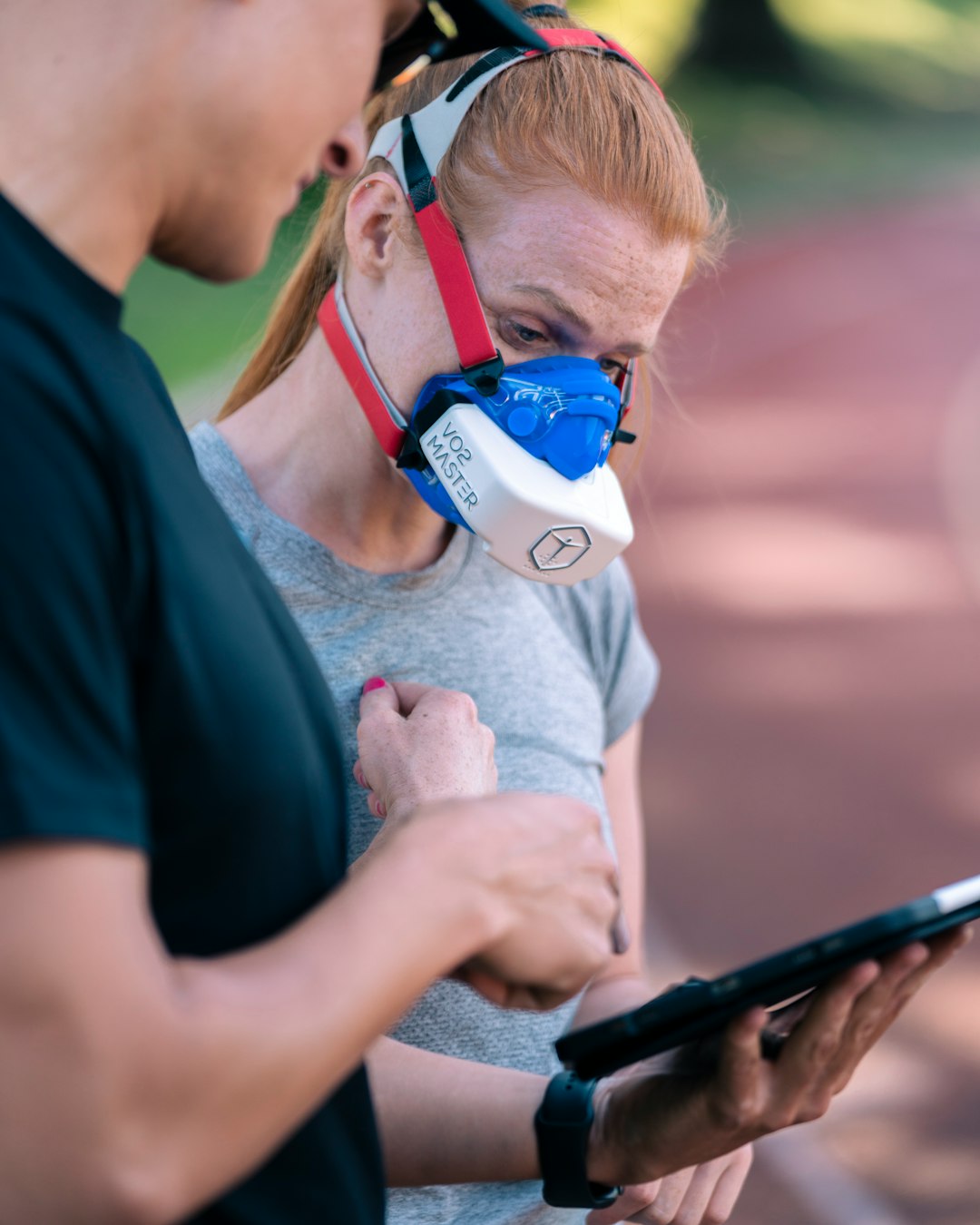 a man and a woman with a breathing mask on looking at a tablet ai fitness tracker, sports wearable, data monitoring