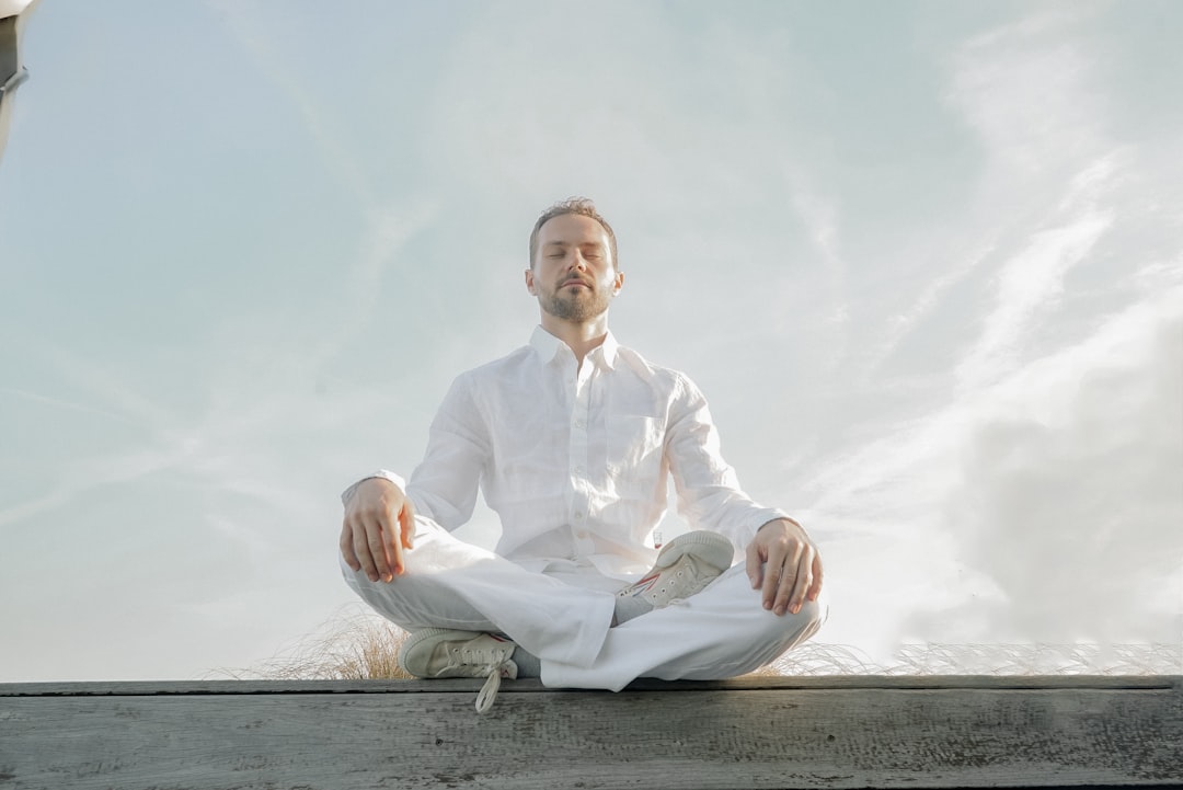 A man in a white shirt and tie sitting in a lotus position rest day, meditation, recovery, wellness