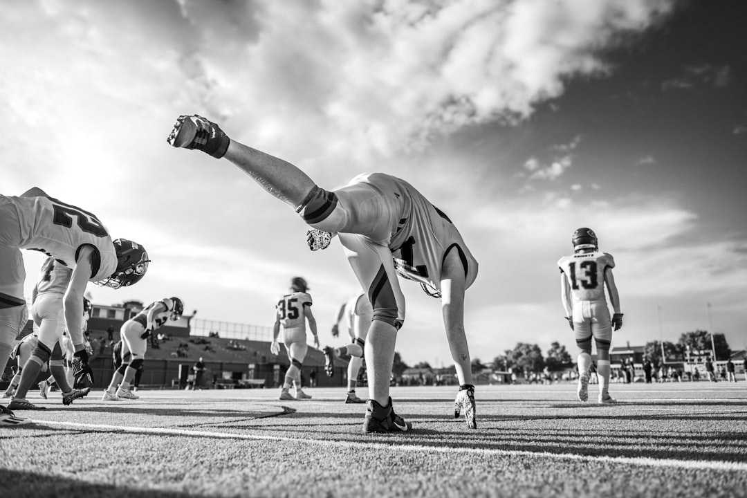 American football players stretching on field during game. high school sports AI data