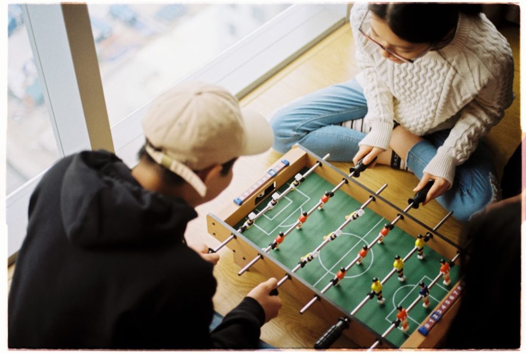 man and woman playing foosball table football parlay betting, sports betting strategy, betting slips