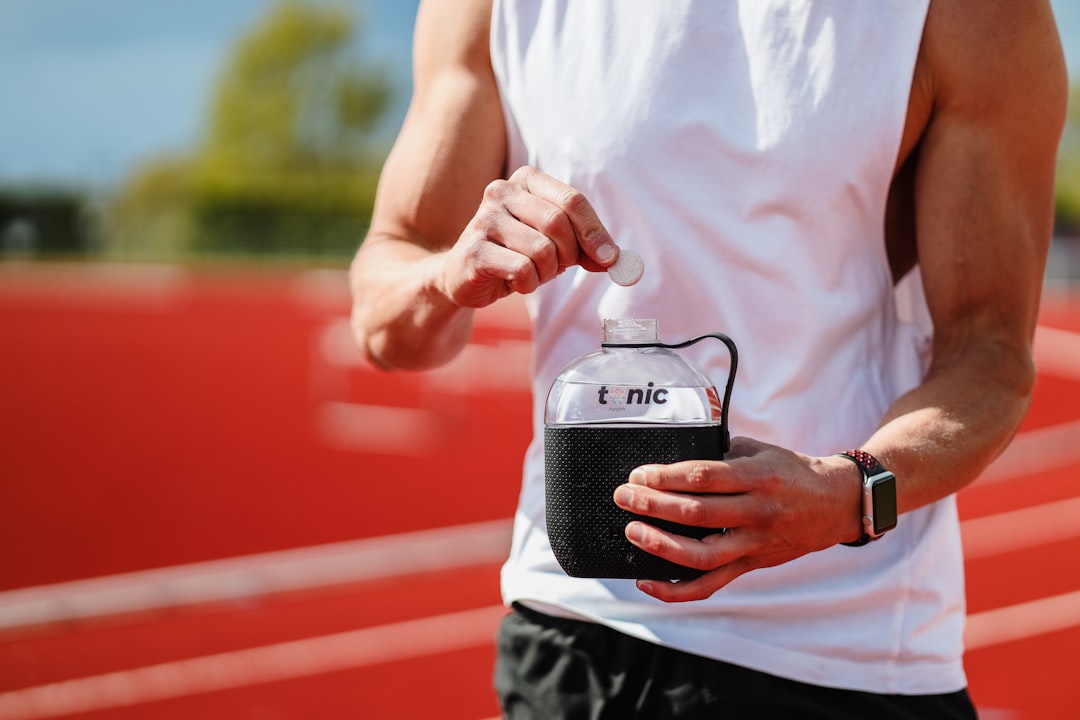 man in white shirt holding black and gray portable speaker wearable tech, athlete training, gps tracker, smartwatch
