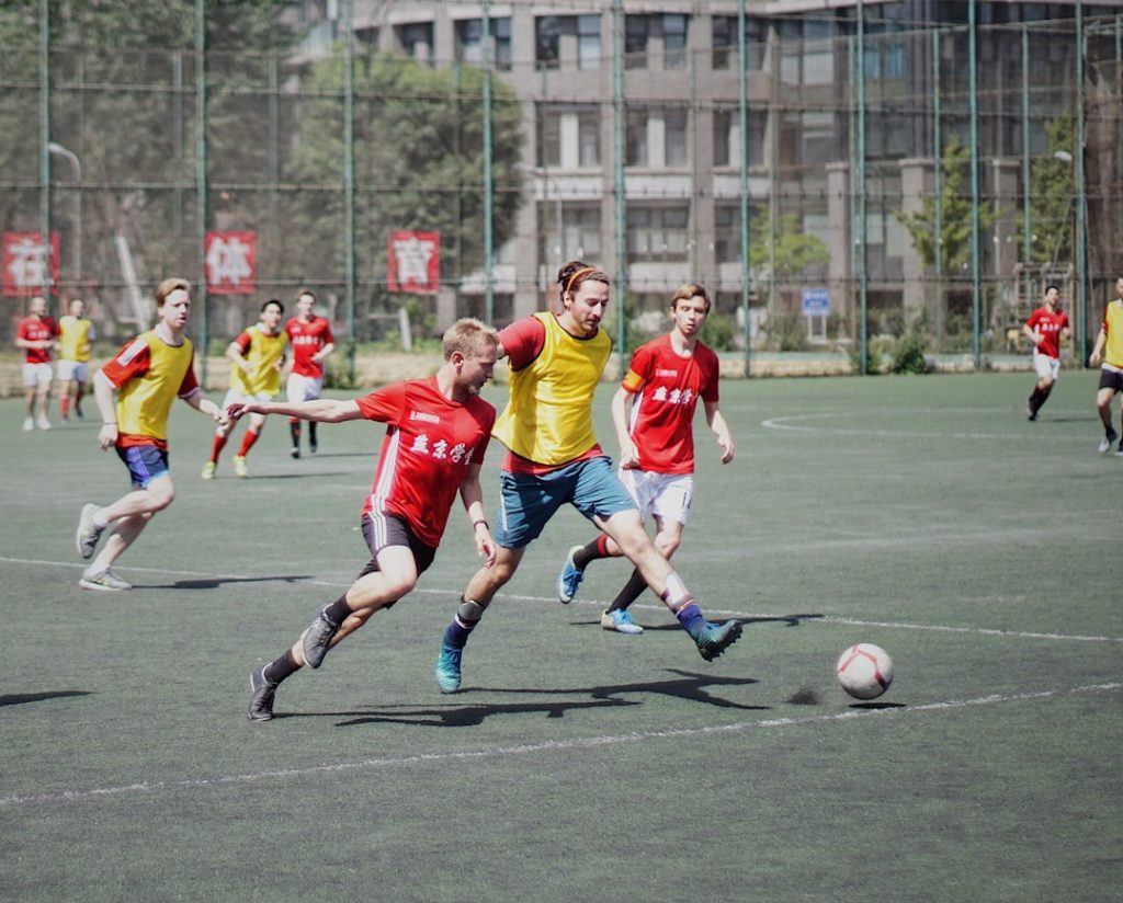 men playing soccer on field with fence kids sports, youth talent, cheering teammates