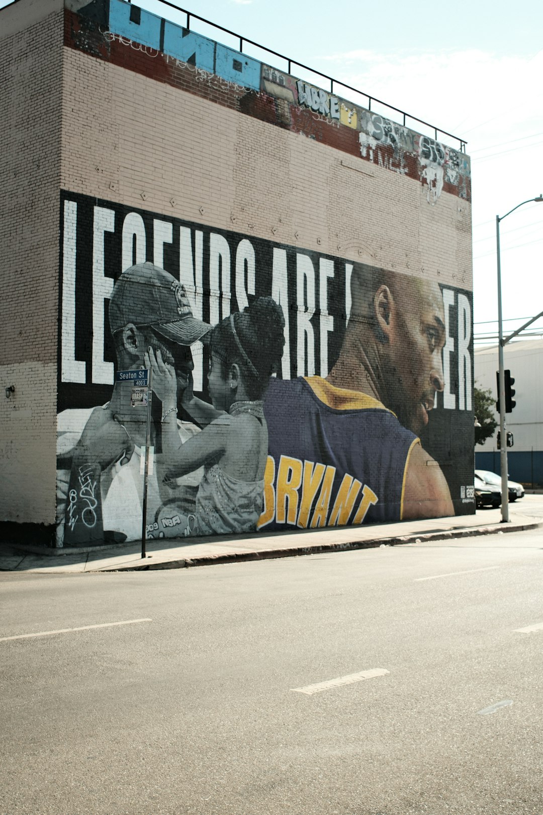 Mural of kobe bryant and children on a brick building. post malone style,fashion courtside,nba culture,mural tribute