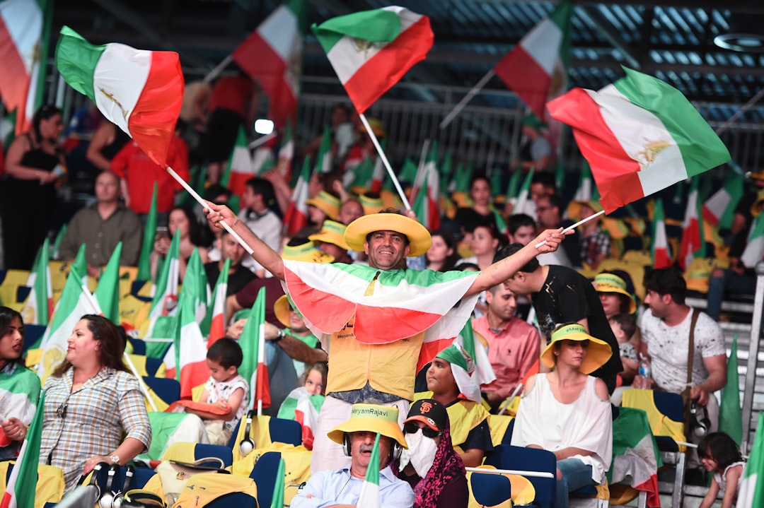 shallow focus photo of man holding flags soccer fans, intense match, stadium atmosphere, rival team flags