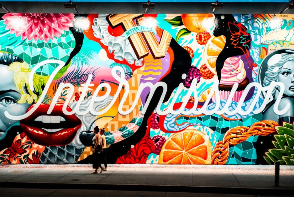 two women walking near multicolored graffiti art post malone style,fashion courtside,nba culture,mural tribute