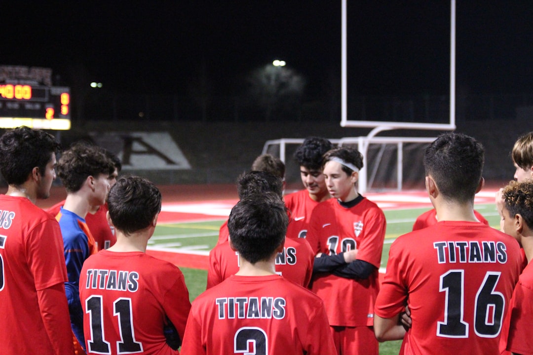 2 men in red soccer jersey team huddle, coach talking, inspirational moment