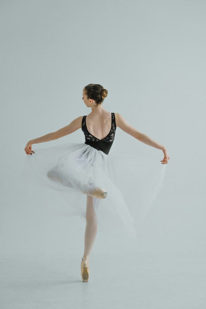 a ballerina in a black leotard and white tulle ballet dancer, emotional expression, artistic dance