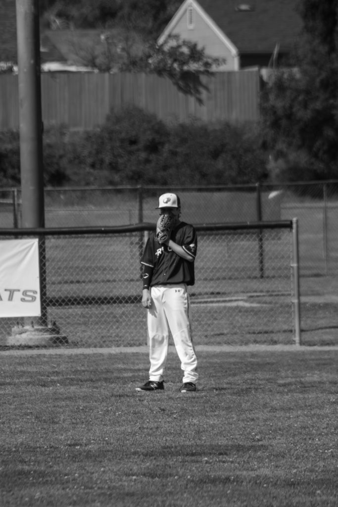 A baseball player stands on the field. little league coach umpire baseball field