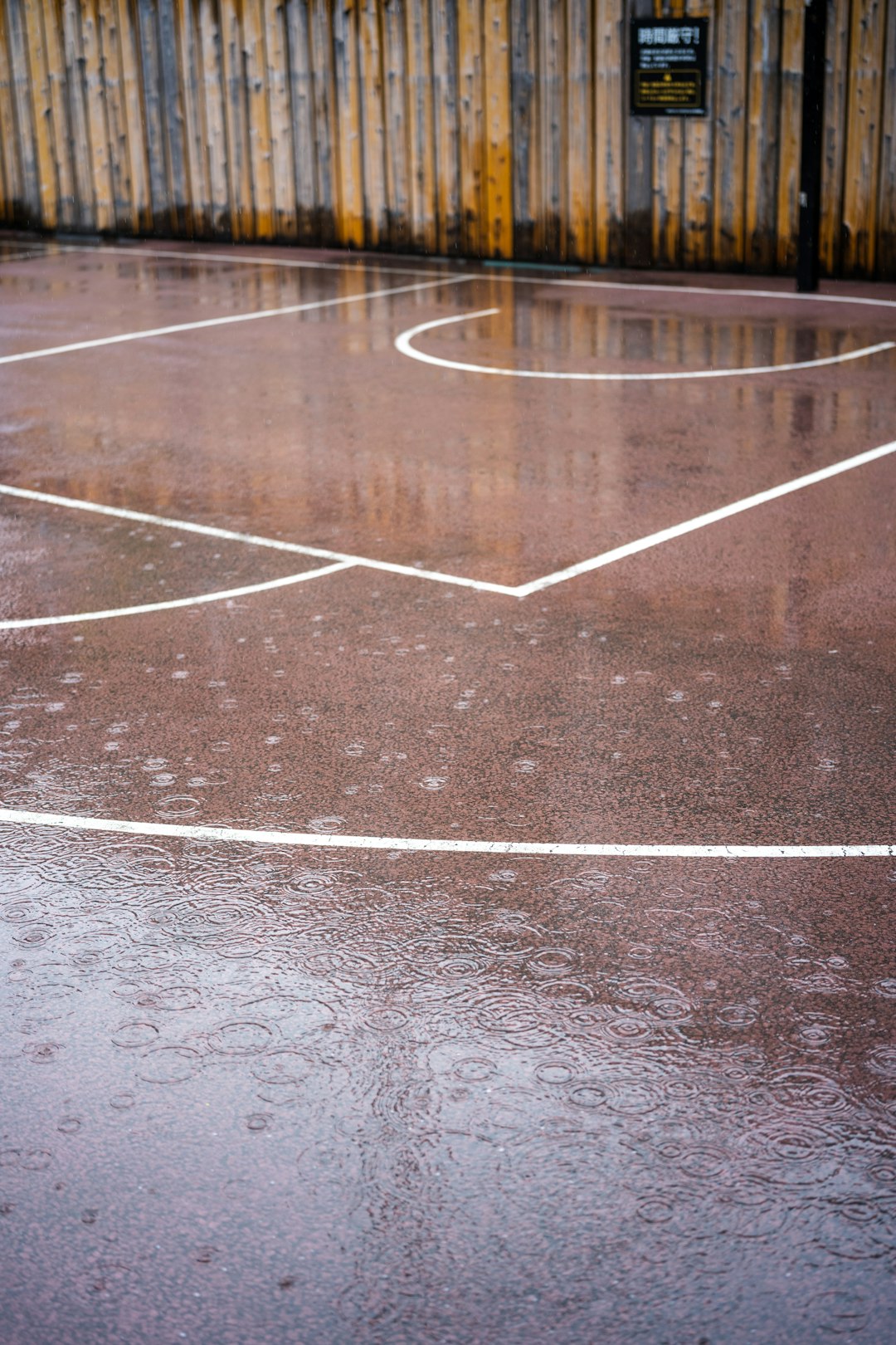 a basketball court with a line painted on it football game rain, outdoor sports weather, athlete cold conditions