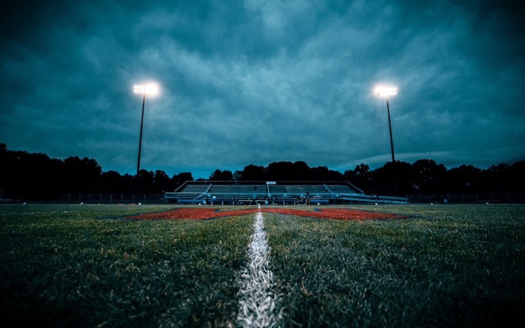 a field with a fountain in it football game rain, outdoor sports weather, athlete cold conditions