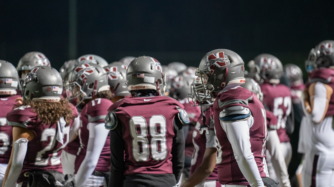 A group of football players standing next to each other teambuilding activities, high school football huddle, players bonding