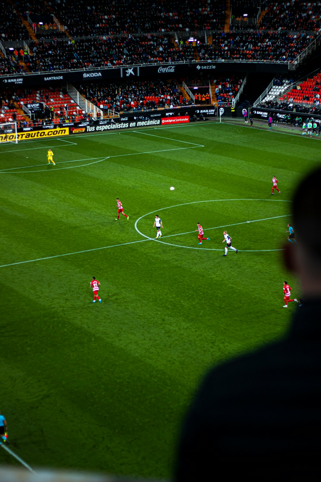 a group of people on a field playing soccer referee reviewing play football monitor stadium
