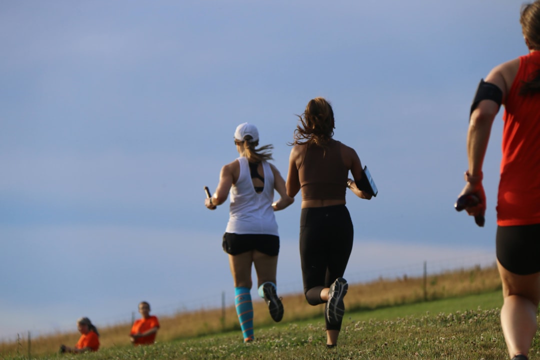 a group of people running on a grass field cross country team, runners trail, fall practice