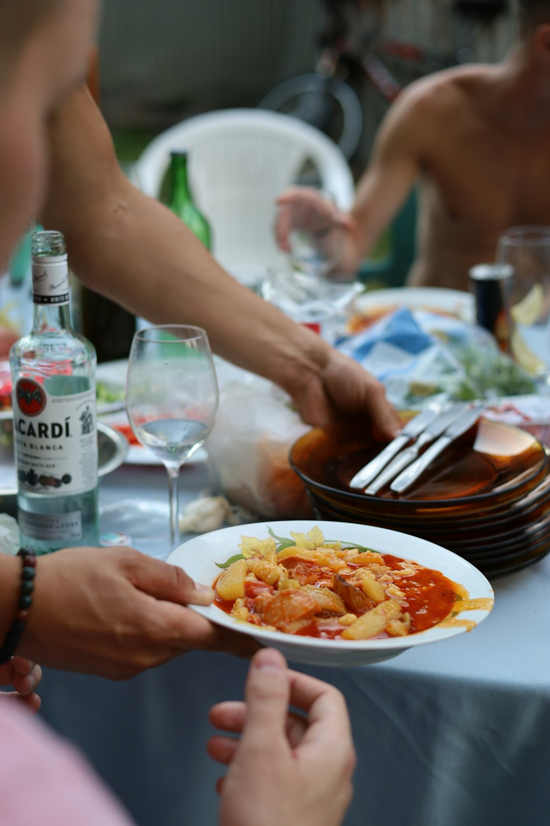 a group of people sitting around a table with plates of food family dining, Mediterranean food, healthy meals, outdoor restaurant
