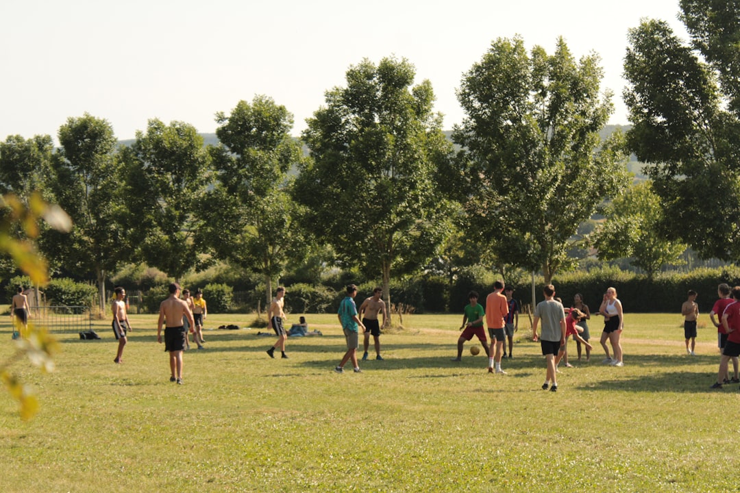 a group of people standing on top of a lush green field wicksburg football training, high school athletes lifting, early morning practice