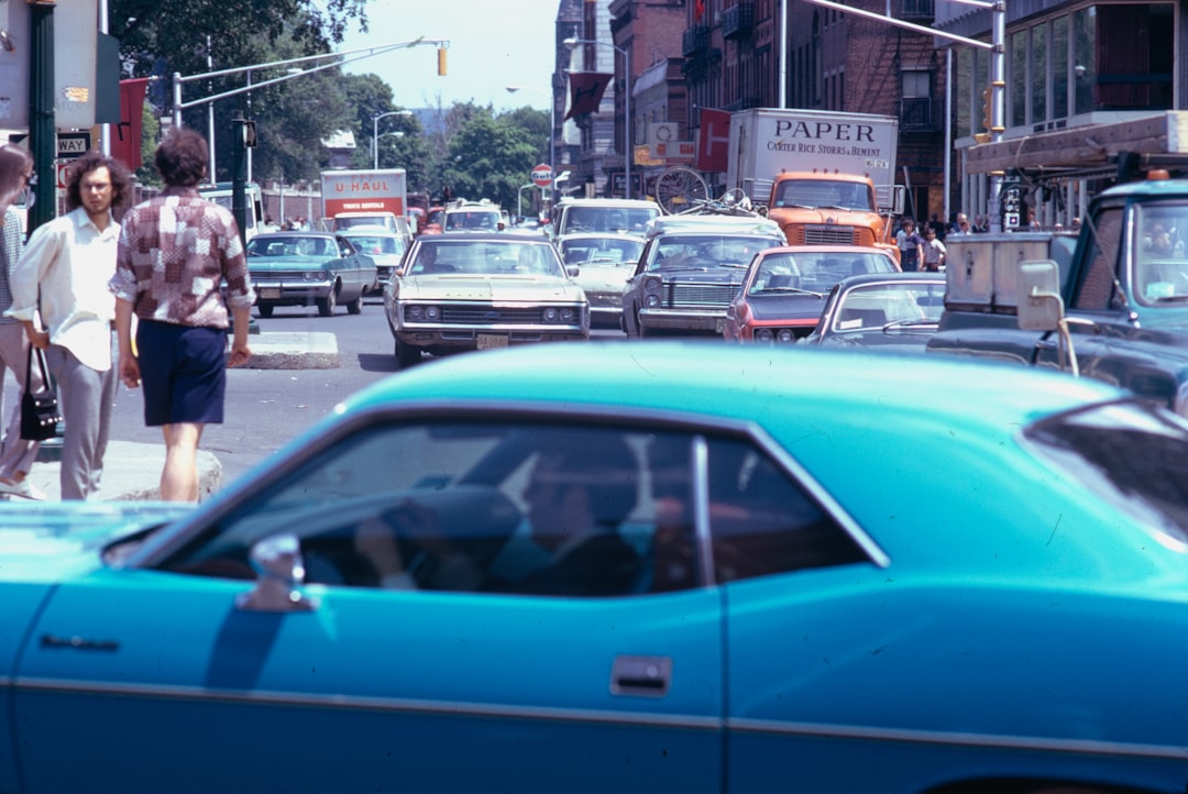a group of people walking down a street next to a blue car jackie robinson, brooklyn dodgers, breaking color barrier