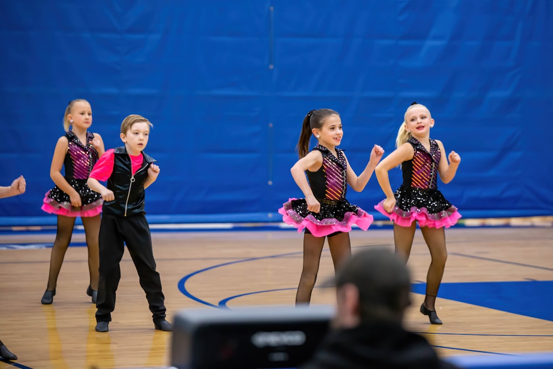 a group of young girls standing on top of a basketball court competitive ballroom dance, dance competition, athletic dancers