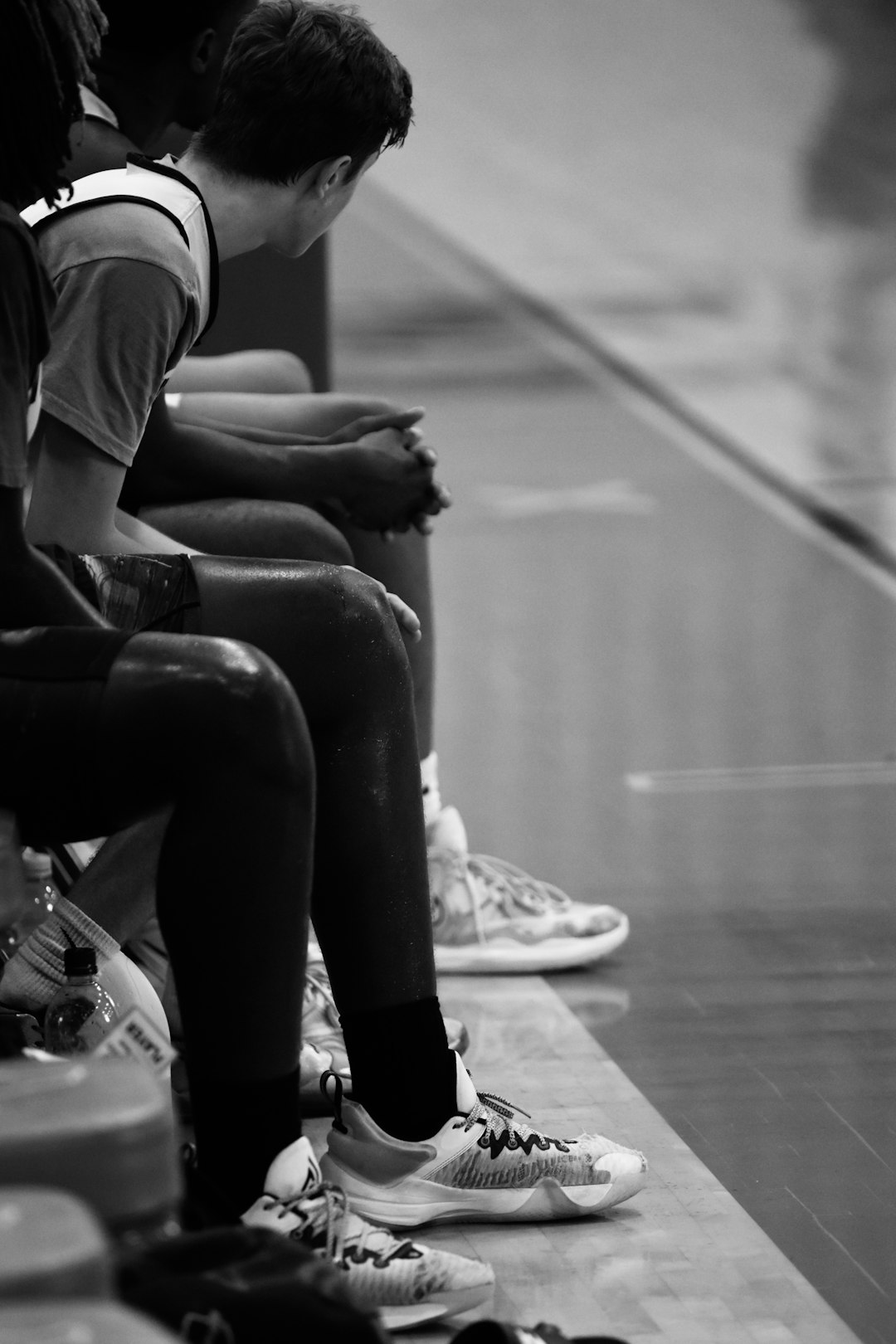 a group of young men sitting on top of a basketball court rookie player coach bench sideline
