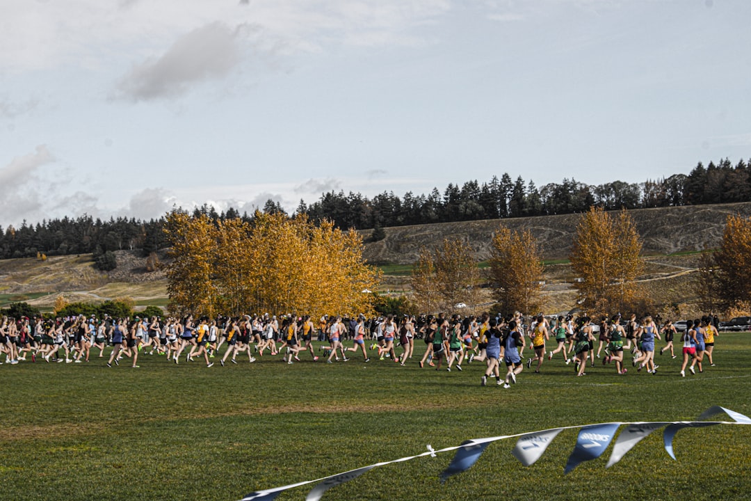 A large group of people running in a field cross country team, runners trail, fall practice