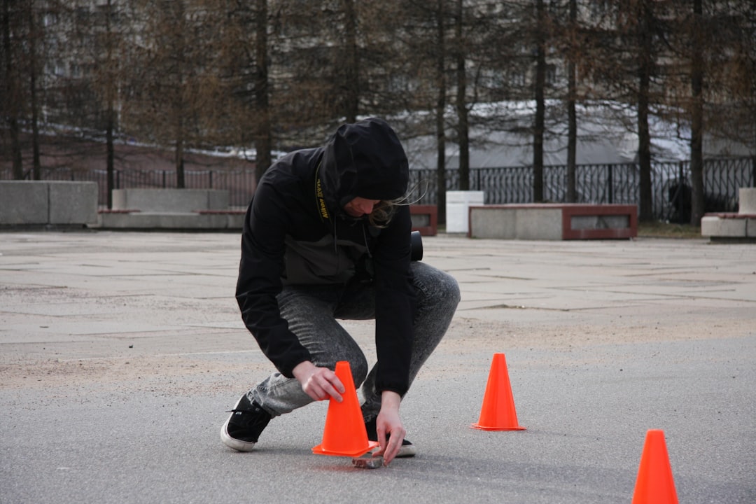 A man crouching down to pick up an orange cone ladder drill, cone drill, speed training, football agility