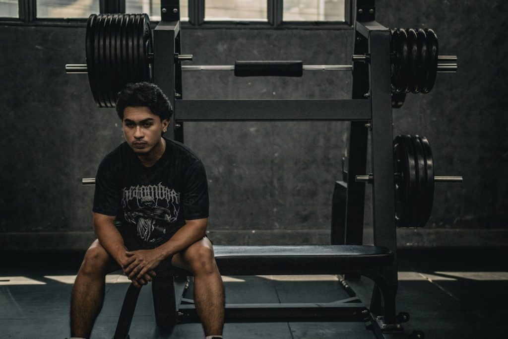 A man sitting on a bench in a gym sad person, losing streak, motivation