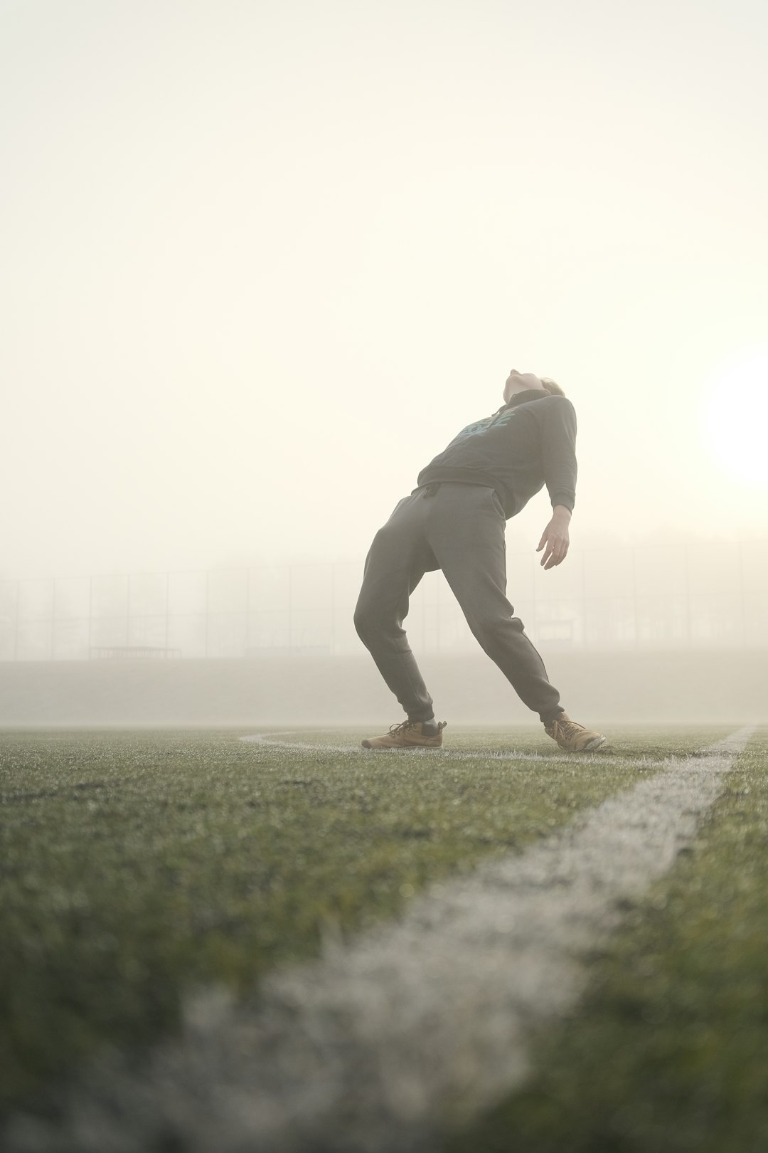 A man stretches on a foggy field. football player retirement, planning future, athlete transition
