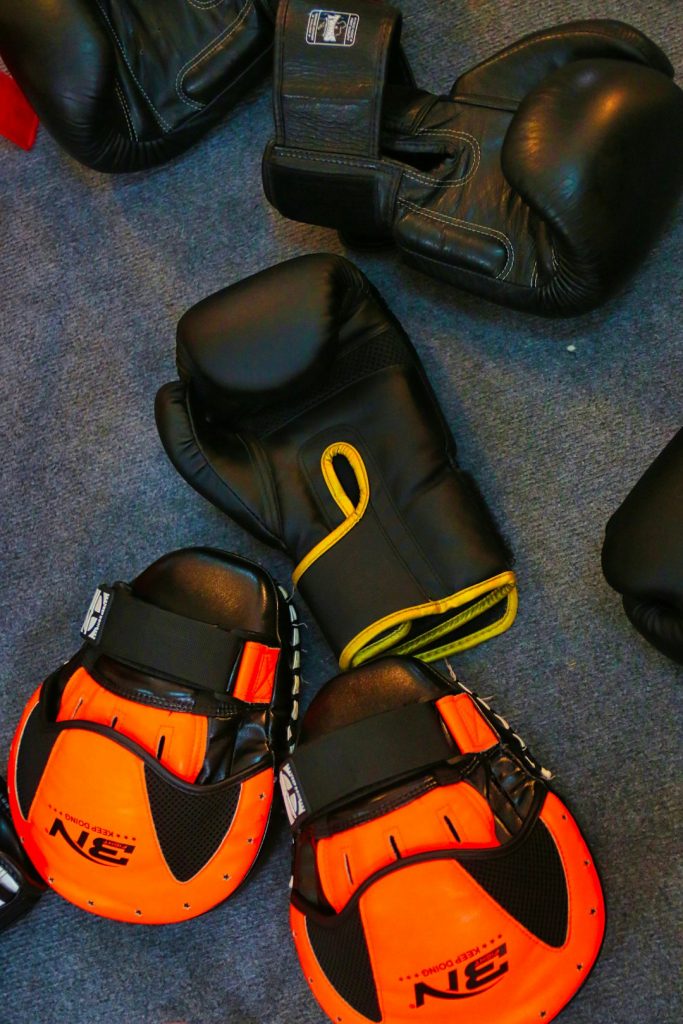 a pair of black and orange boxing gloves athletes gear, ankle brace, sports bag