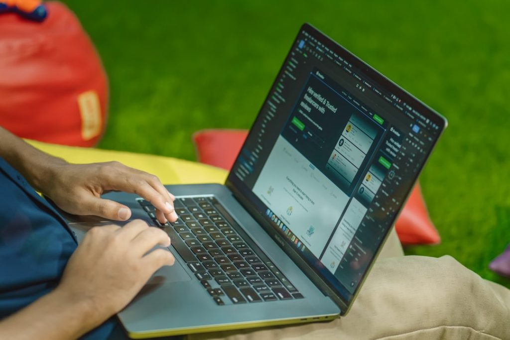 a person sitting on the grass using a laptop coach laptop synergy video analysis