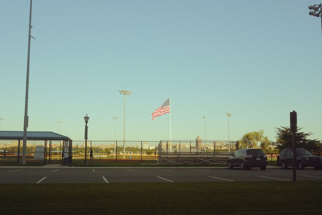 a road with cars and a flag on it wicksburg football training, high school athletes lifting, early morning practice