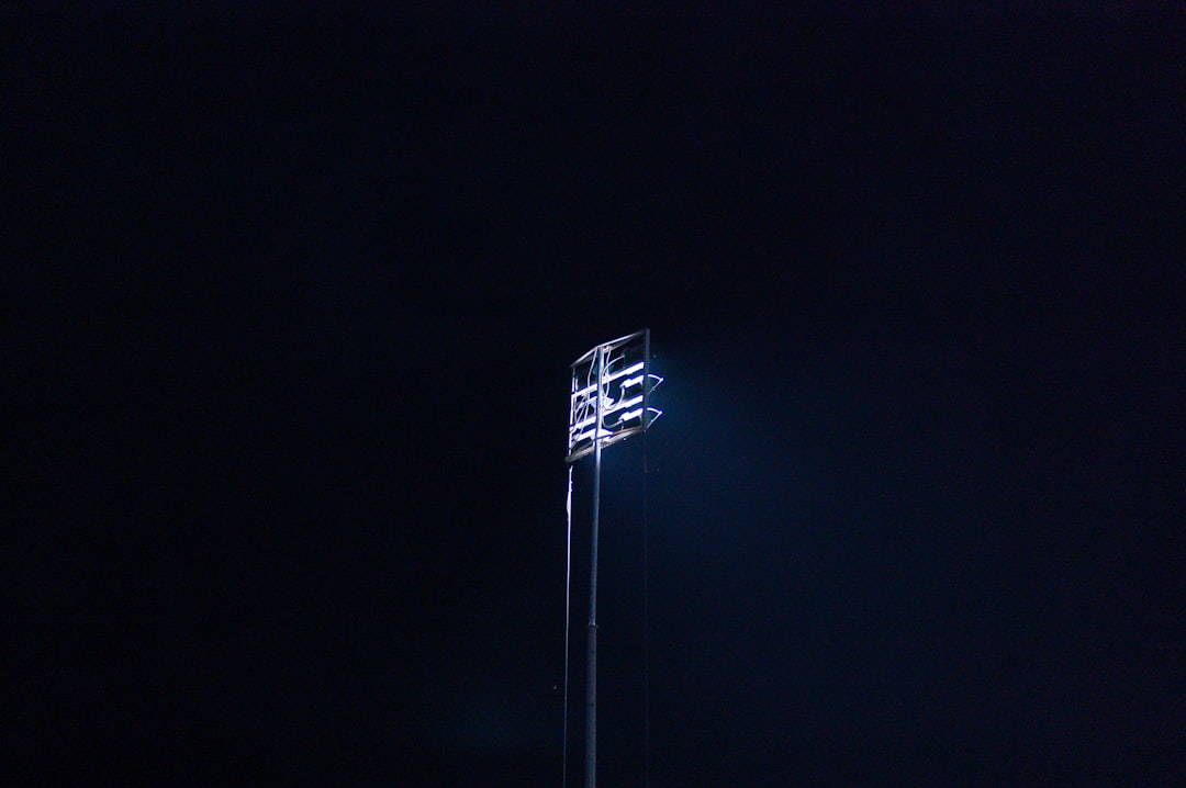a street light in the dark with a sky background friday night lights, high school football game, packed stadium cheering
