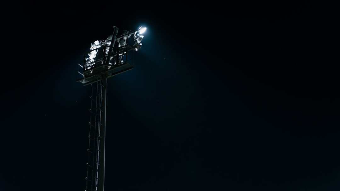 a tall metal pole with a bunch of lights on top of it friday night lights, high school football game, packed stadium cheering