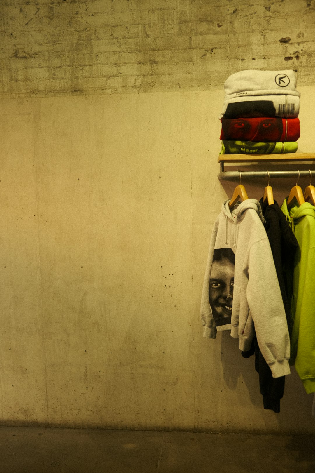 Clothes are stacked and hung in front of a wall. football gear fitting, player trying vest, locker room