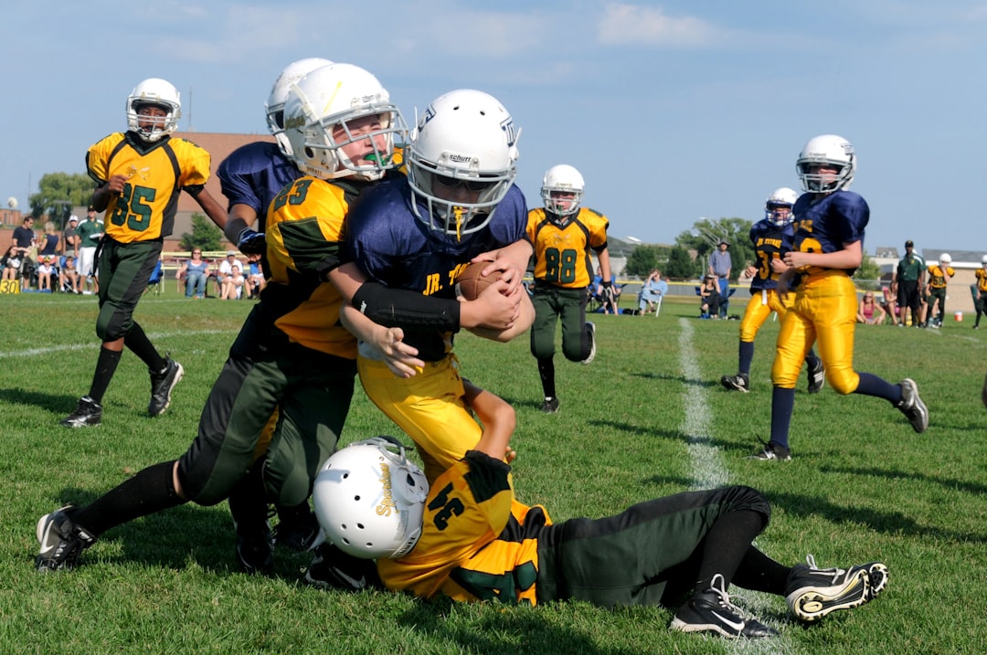 football players struggling to hold the football during daytime teambuilding activities, high school football huddle, players bonding
