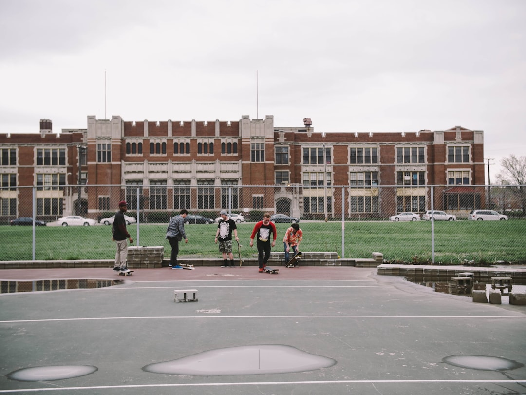 group of people near brown building football players scoreboard high school