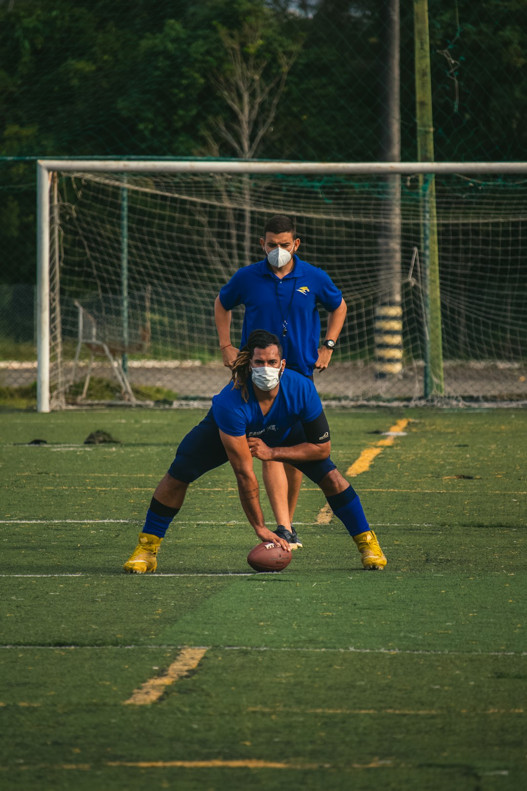 man in blue soccer jersey kicking soccer ball on green grass field during daytime football injury player medical trainers