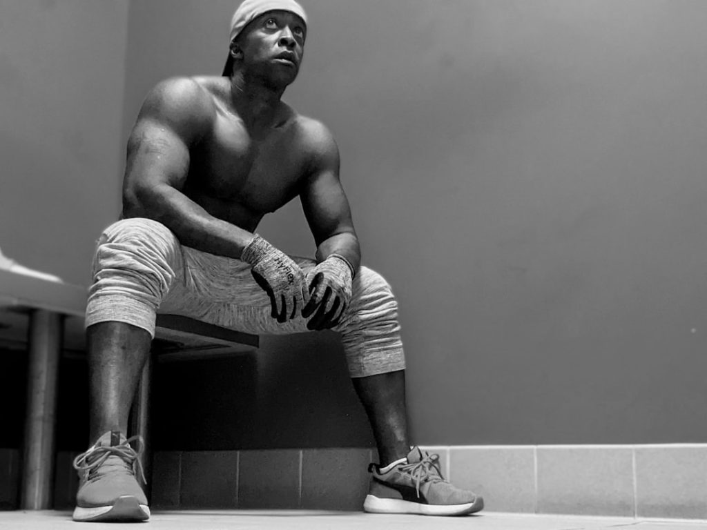 man in white and black stripe shorts and sneakers sitting on the floor nfl players, football roster cuts, athlete tryouts