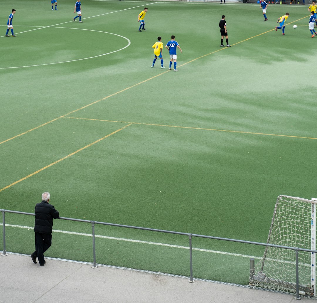 people playing soccer on green field during daytime referee reviewing play football monitor stadium