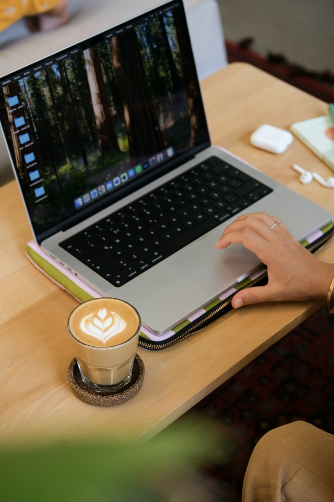 Person working on laptop with latte art coffee. content editing workflow laptop coffee notes