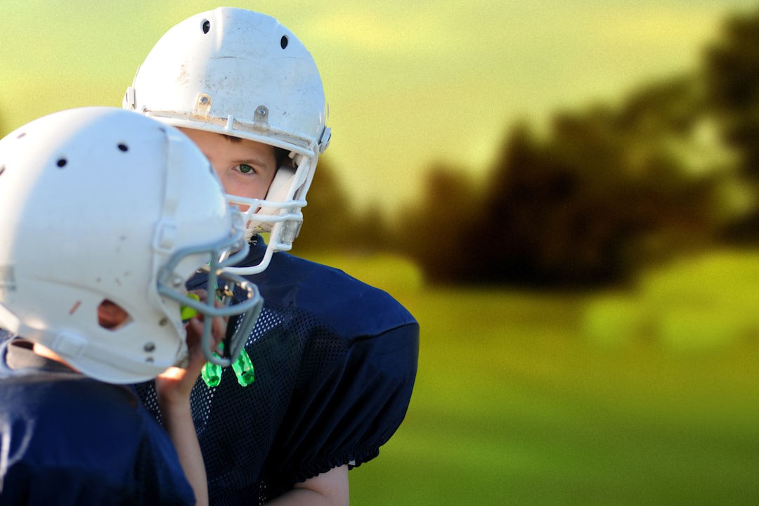 selective focus photography of two football players football helmet smart technology coaching sideline