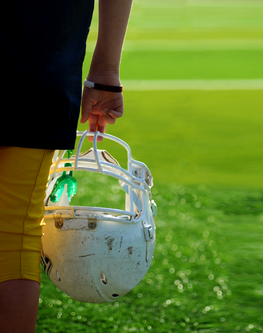 shallow focus photography of football player holding helmet football helmet smart technology coaching sideline