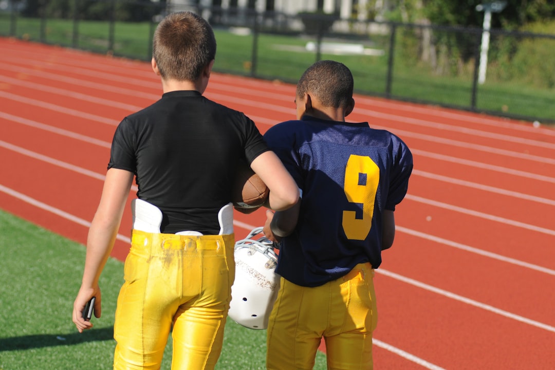 two boys walking on green field at daytime wicksburg football training, high school athletes lifting, early morning practice