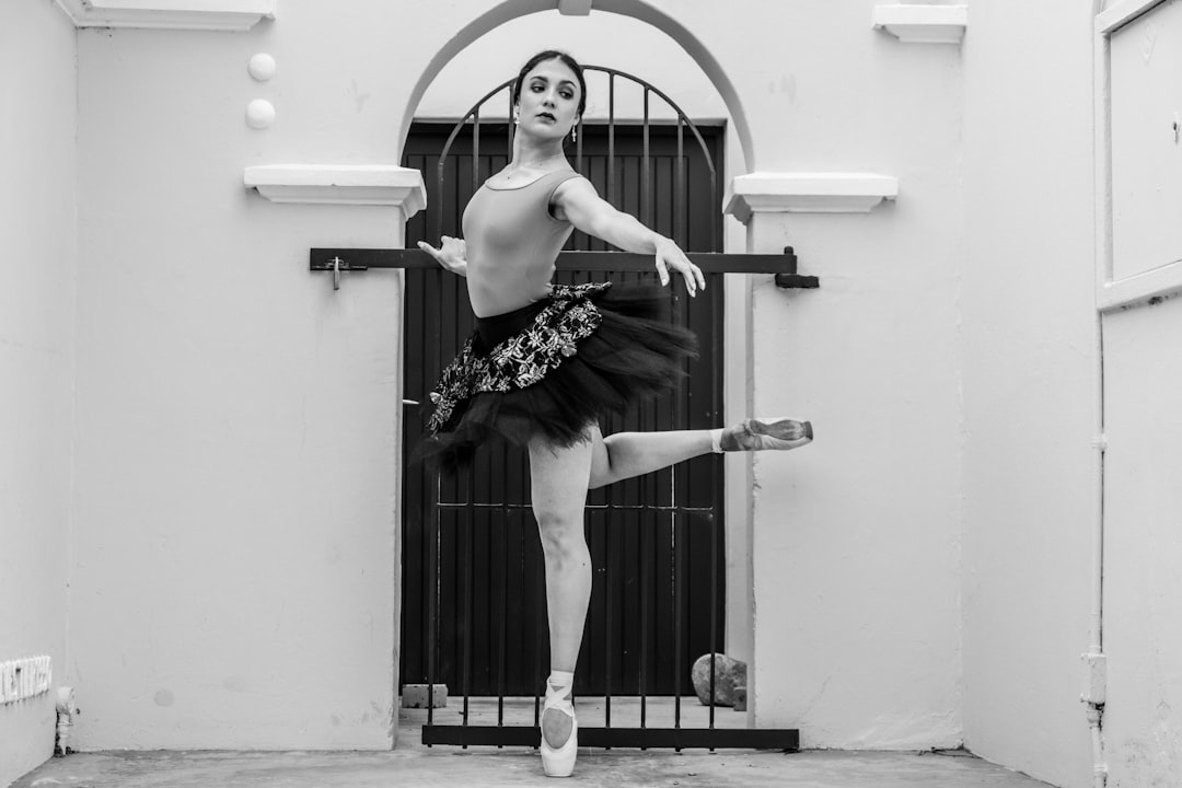 woman in black and white floral dress jumping on white wall ballet, strength, dance training