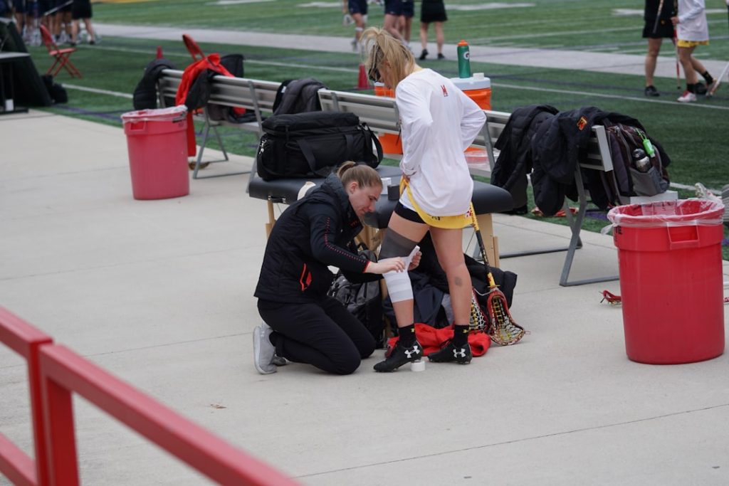 woman taping knee of woman football injury player medical trainers